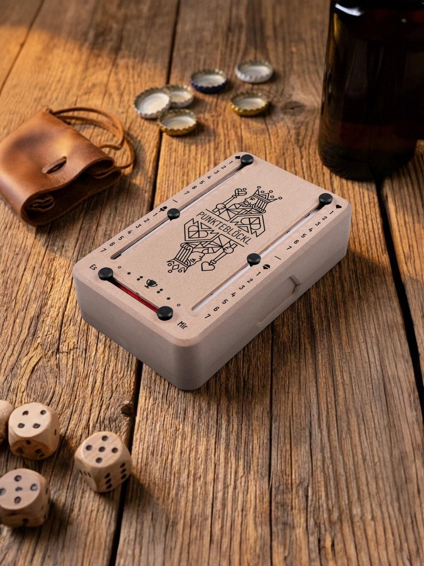 Punkteblöckl in Holzoptik mit schwarzen Pins und KoenigKoenigin-Motiv. Platziert auf Holztisch mit Würfeln und Kronkorken.